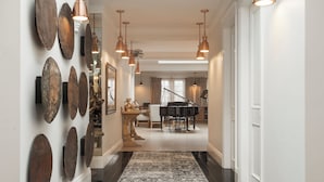 A hallway with a patterned carpet, wall-mounted decorative plates, and hanging pendant lights.