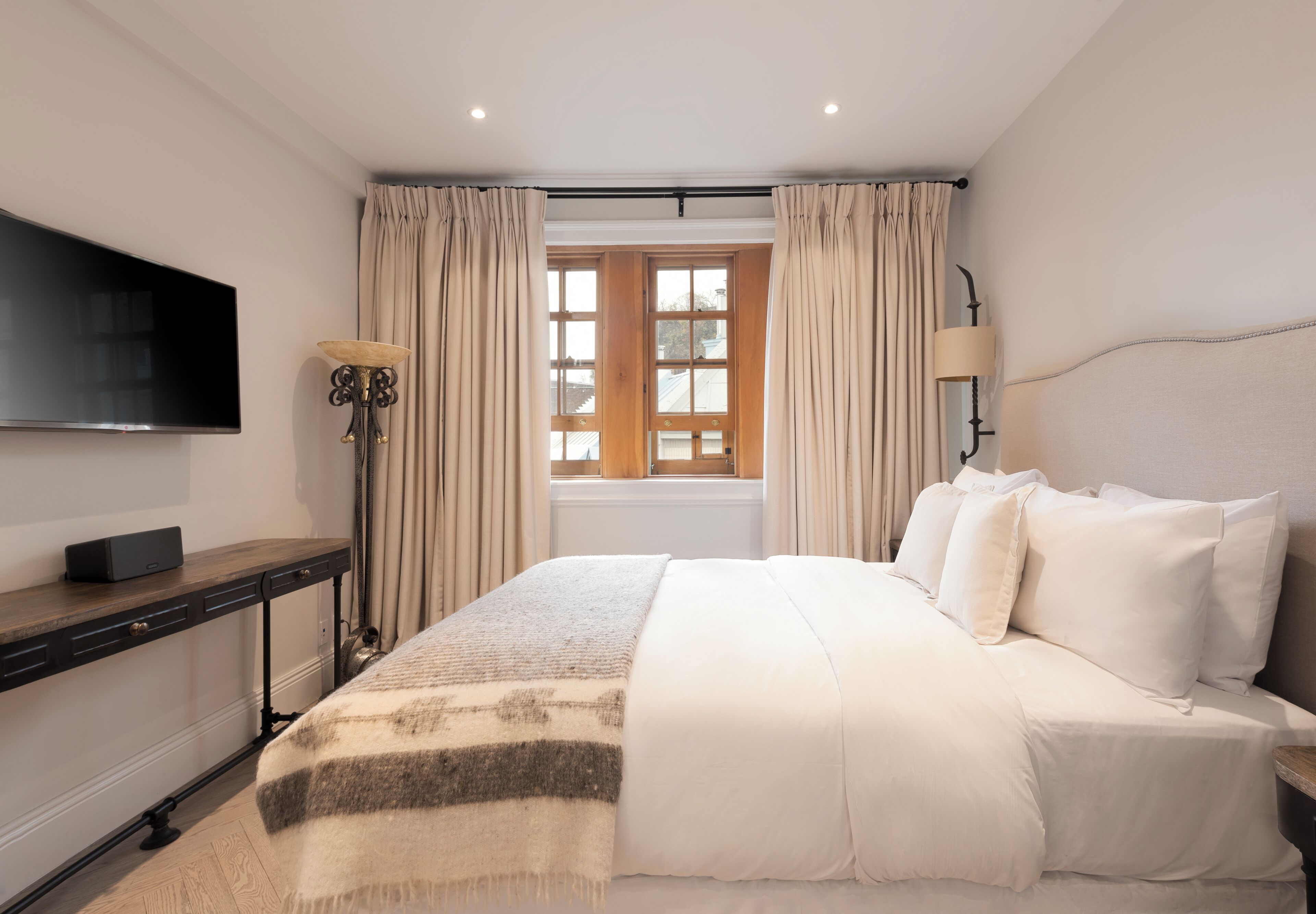 Habitación de hotel con cama, televisión de pantalla plana, escritorio y ventana con cortinas.