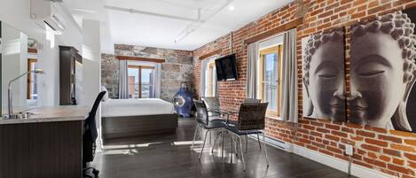 A modern hotel room with a brick wall, a large Buddha painting, a bed, a desk, and a chair.
