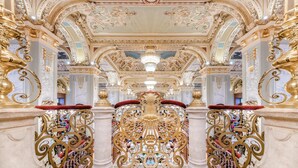 Un interior ornamentado con detalles en oro elaborados y un candelabro central.