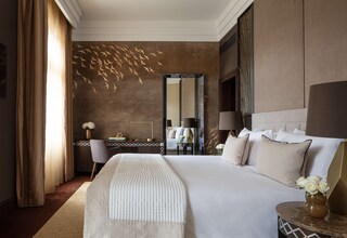 A hotel room with a large bed, a mirror, a desk, and a vase with flowers.