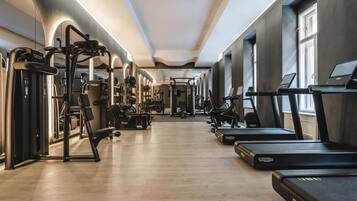 Uma academia moderna com diversos equipamentos de exercício, incluindo esteiras e aparelhos de musculação, dispostos em um espaço amplo com grandes janelas que oferecem luz natural.