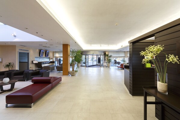 Un hall d’entrée moderne avec un comptoir d’accueil, un espace salon et des plantes en pot.