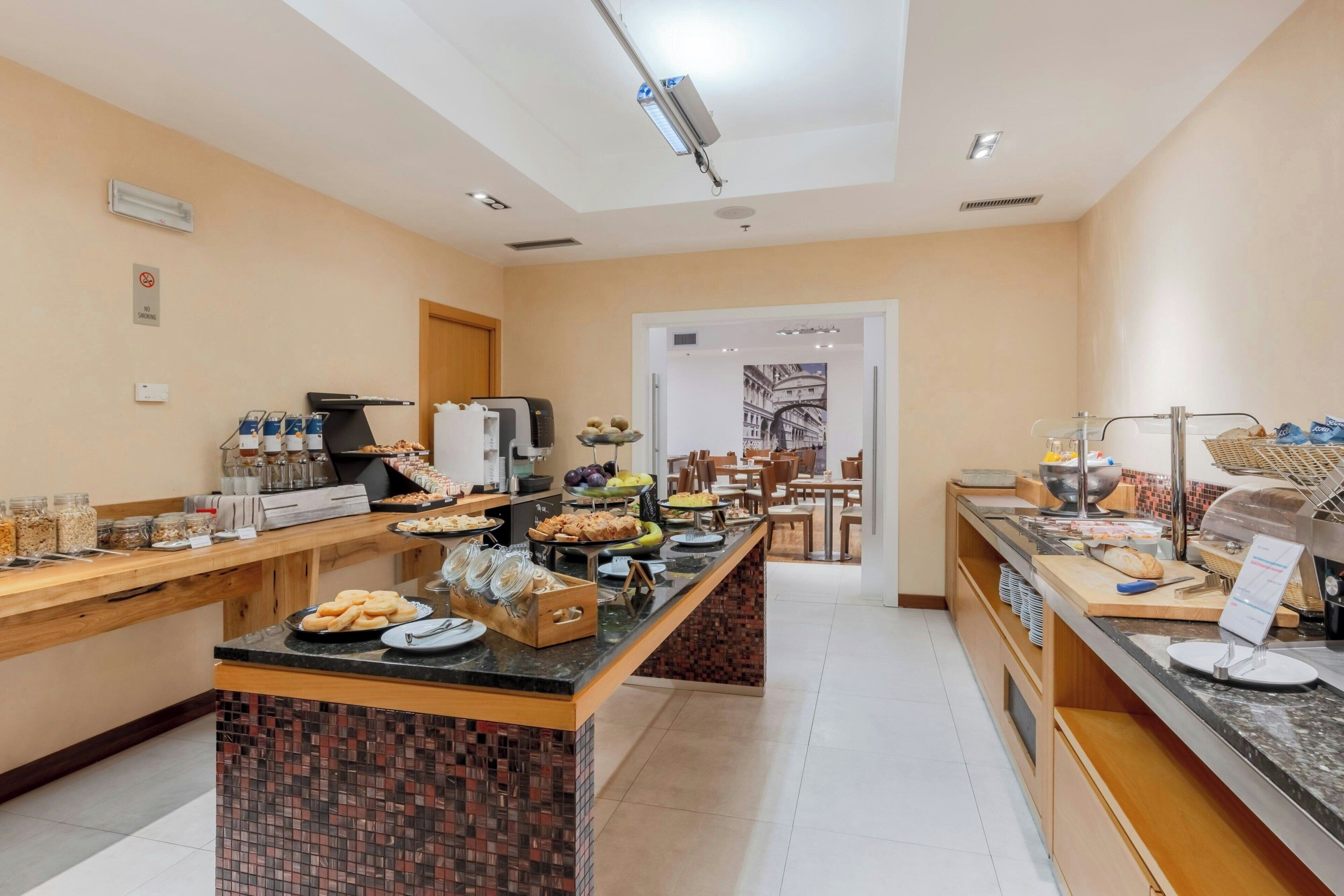 A hotel breakfast area with a buffet setup, including various food items and a coffee station.