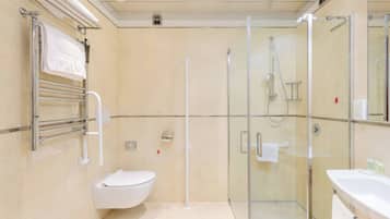 A modern bathroom with a glass-enclosed shower, a toilet, and a sink.