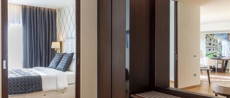 A modern hotel room with a bed, a large mirror, and a wooden wardrobe.