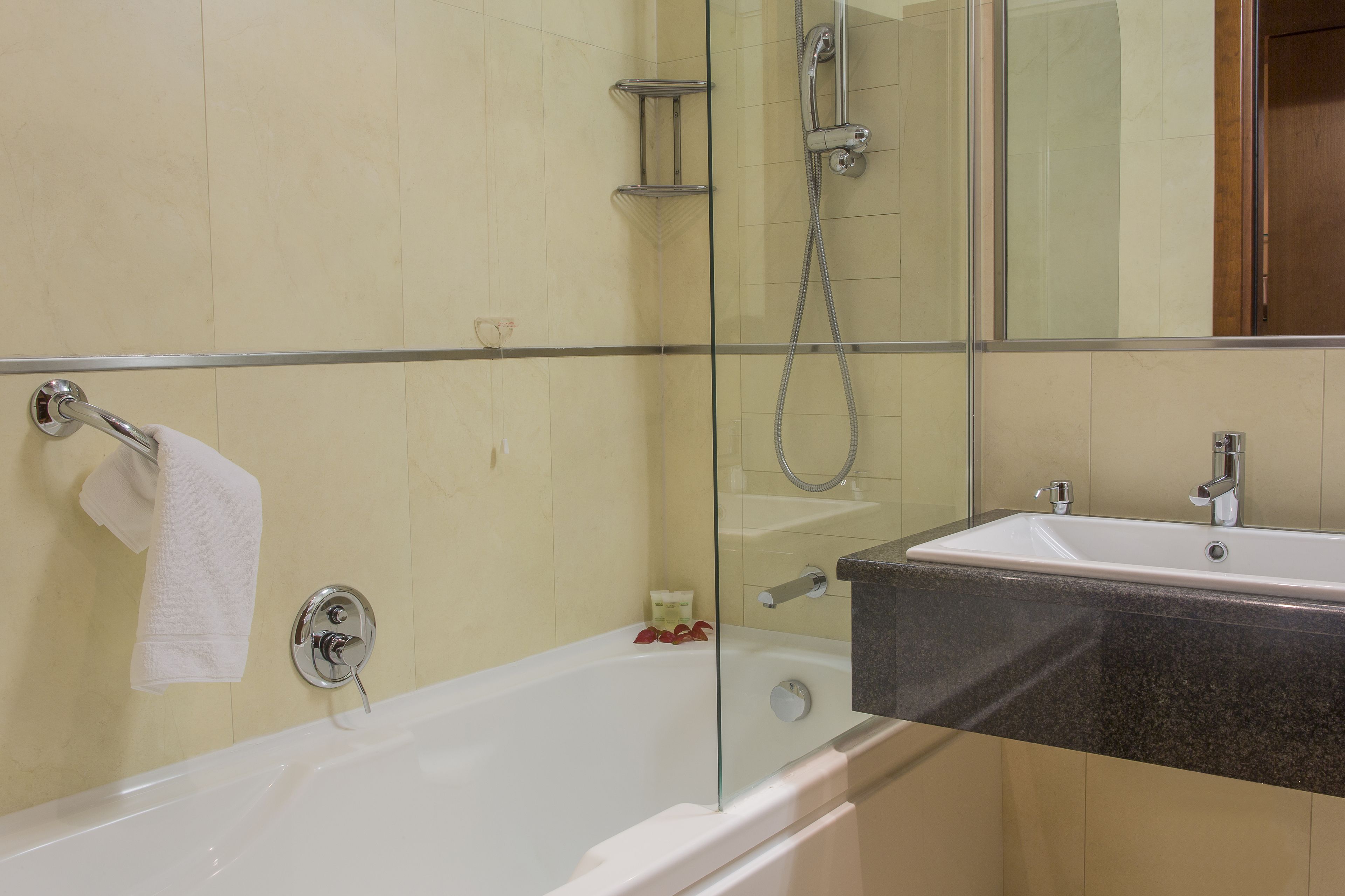 Un baño con cabina de ducha de vidrio, una bañera blanca y un lavabo con encimera de granito.