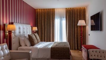 Ein Hotelzimmer mit einem großen Bett, zwei Nachttischen mit Lampen, einem an der Wand montierten Fernseher und einer rot-weiß gestreiften Wand.