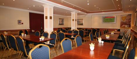 A conference room with multiple tables and chairs, arranged for meetings or dining.