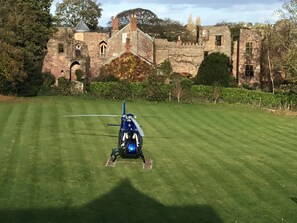 A helicopter on a grassy field with a historic stone building in the background. - The Bridge House Boutique B&B (Ross-on-Wye)