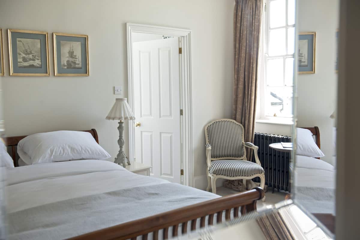 Une chambre d’hôtel avec deux lits, une chaise, une table et une fenêtre avec des rideaux.
