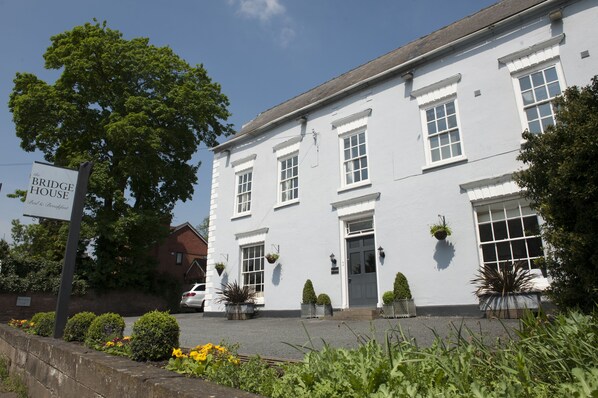 Un edificio blanco con un letrero que dice "The Bridge House Bed & Breakfast".