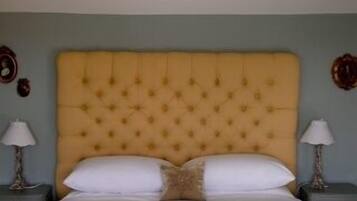 A bed with a tufted headboard, two bedside tables with lamps, and a wall clock.