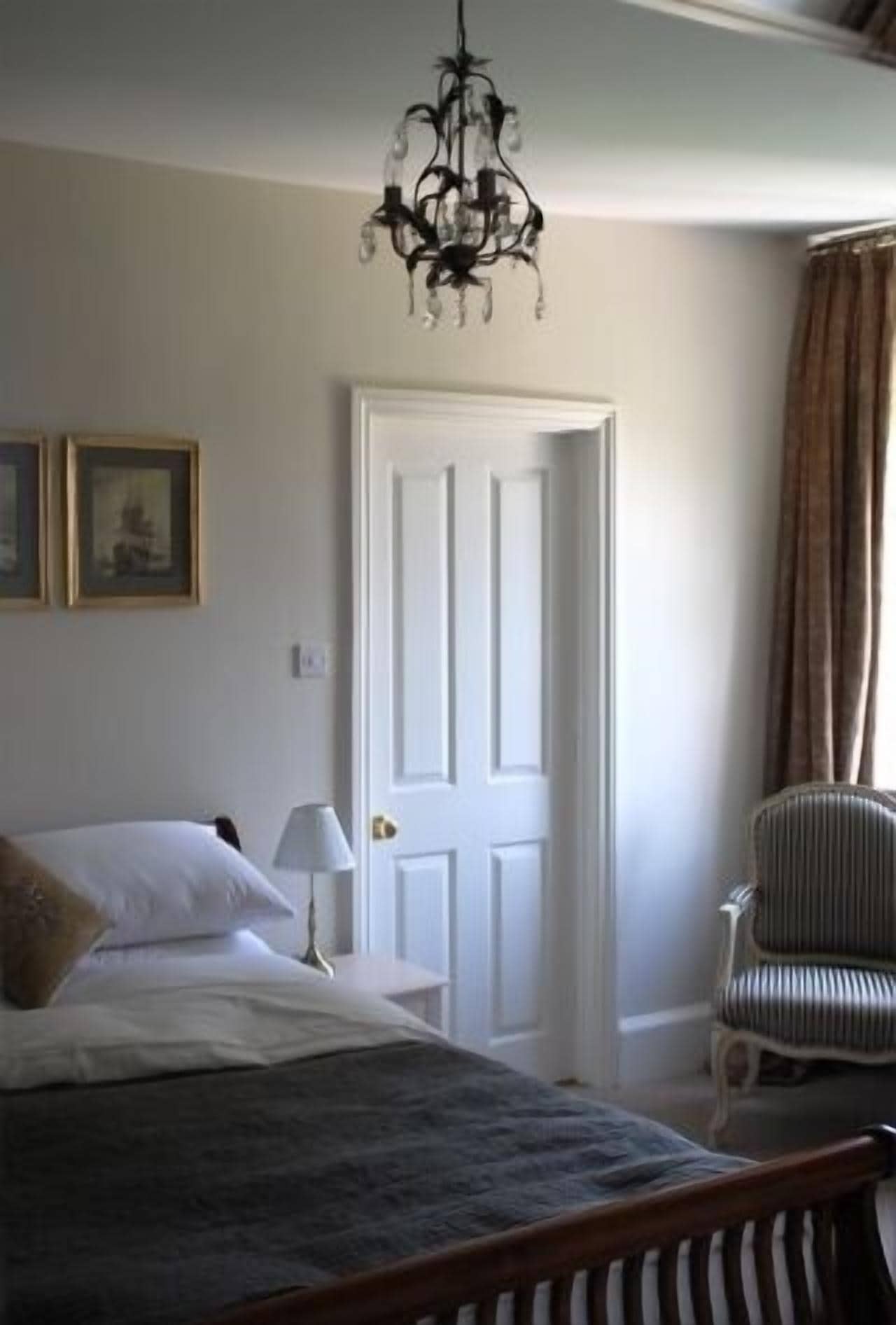 Une chambre à coucher avec un lit, une chaise, une porte et un lustre.