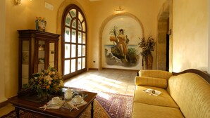 Um hall espaçoso com uma grande porta em arco, um mural, um sofá e uma mesa de centro com um arranjo floral.