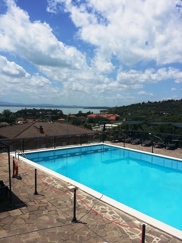 A swimming pool with a view of a lake and distant mountains.