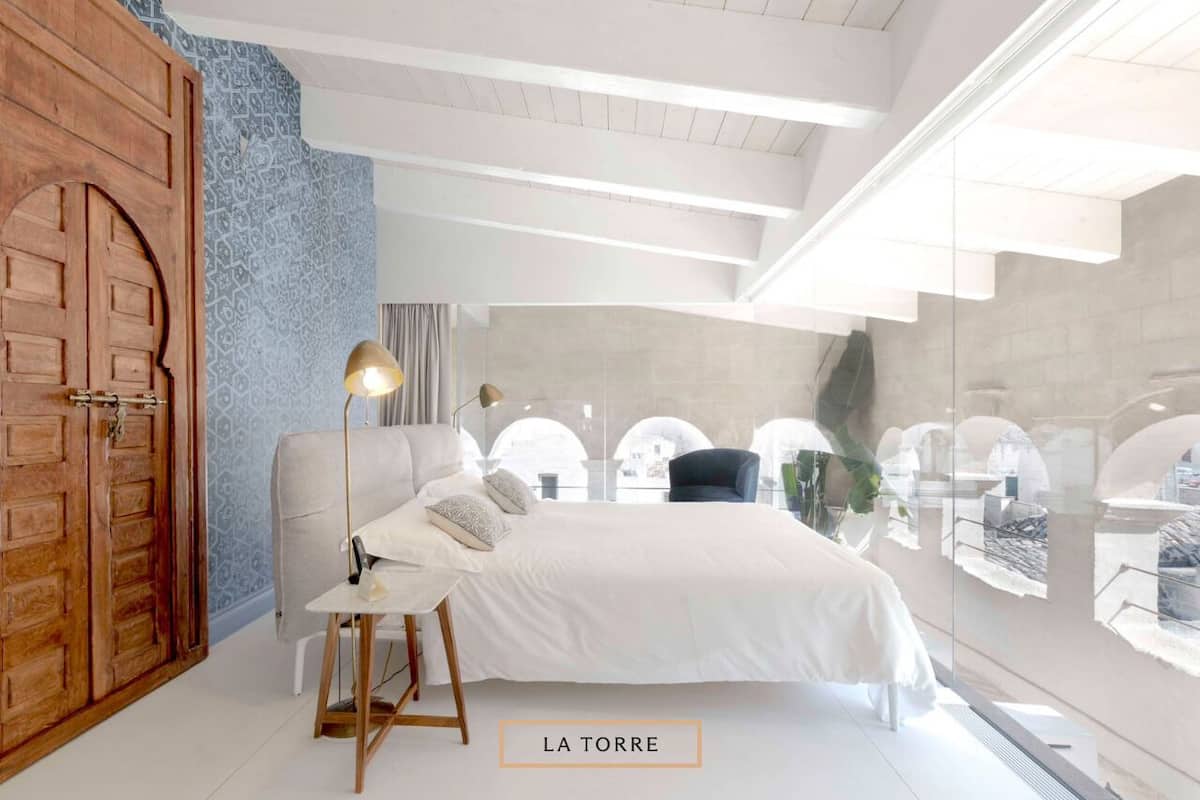 A modern bedroom with a large bed, a wooden wardrobe, a desk, and a chair.