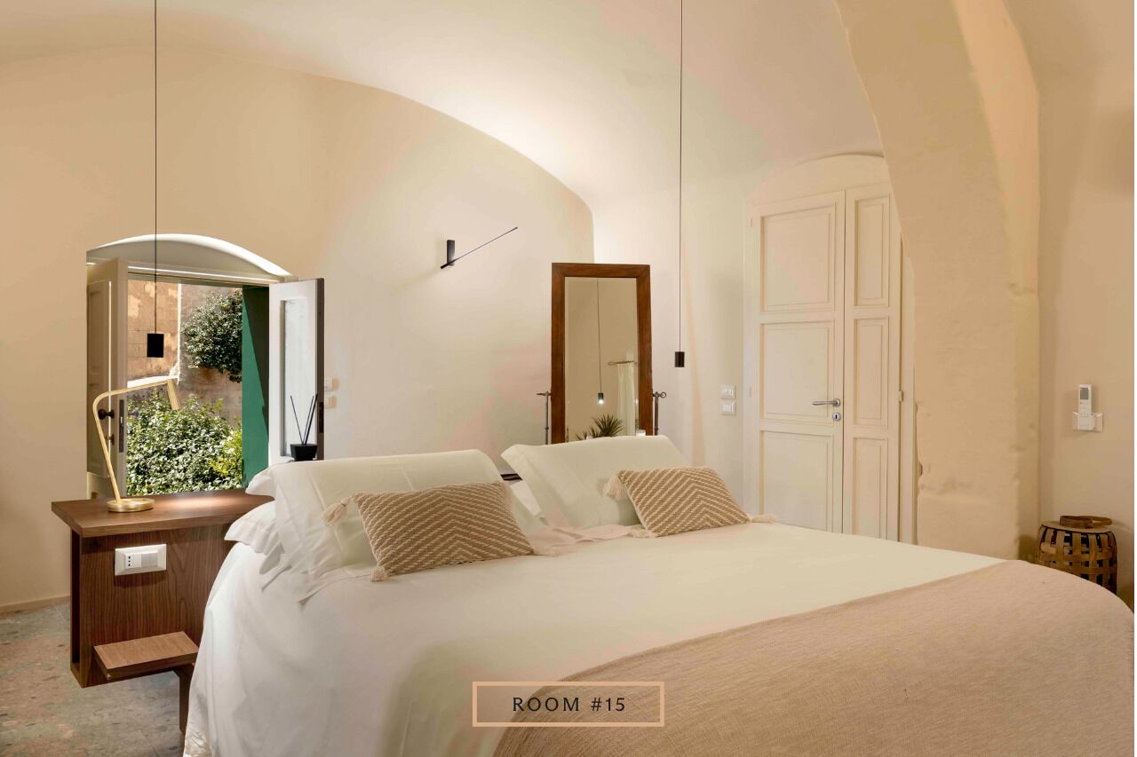 A bedroom with a bed, bedside tables, a mirror, and a door.