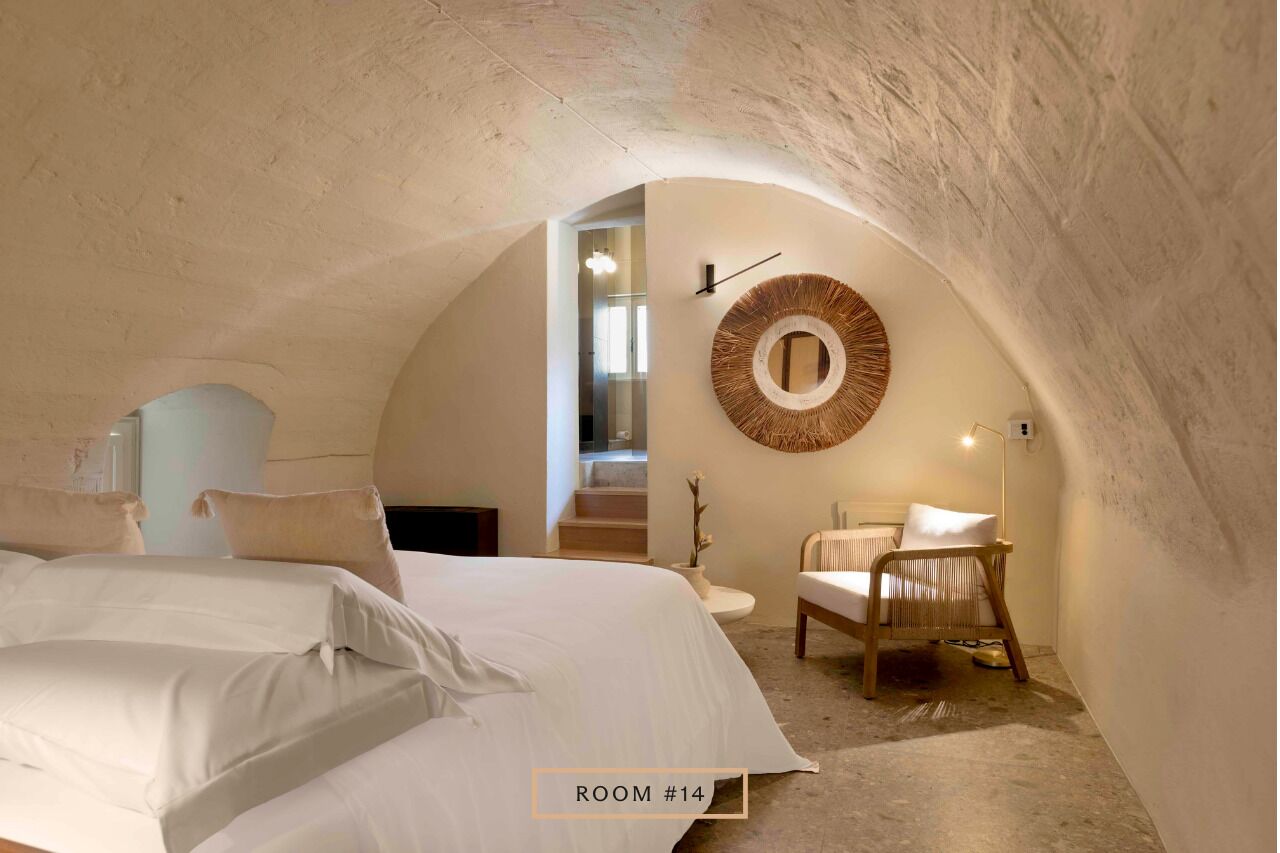 Een gezellige slaapkamer met een groot bed, een ronde spiegel en een stoel.