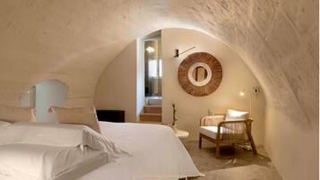 Een gezellige slaapkamer met een groot bed, een ronde spiegel en een stoel.
