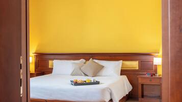 Une chambre d’hôtel avec un lit en bois, du linge de lit blanc et un plateau contenant des articles pour le petit-déjeuner.