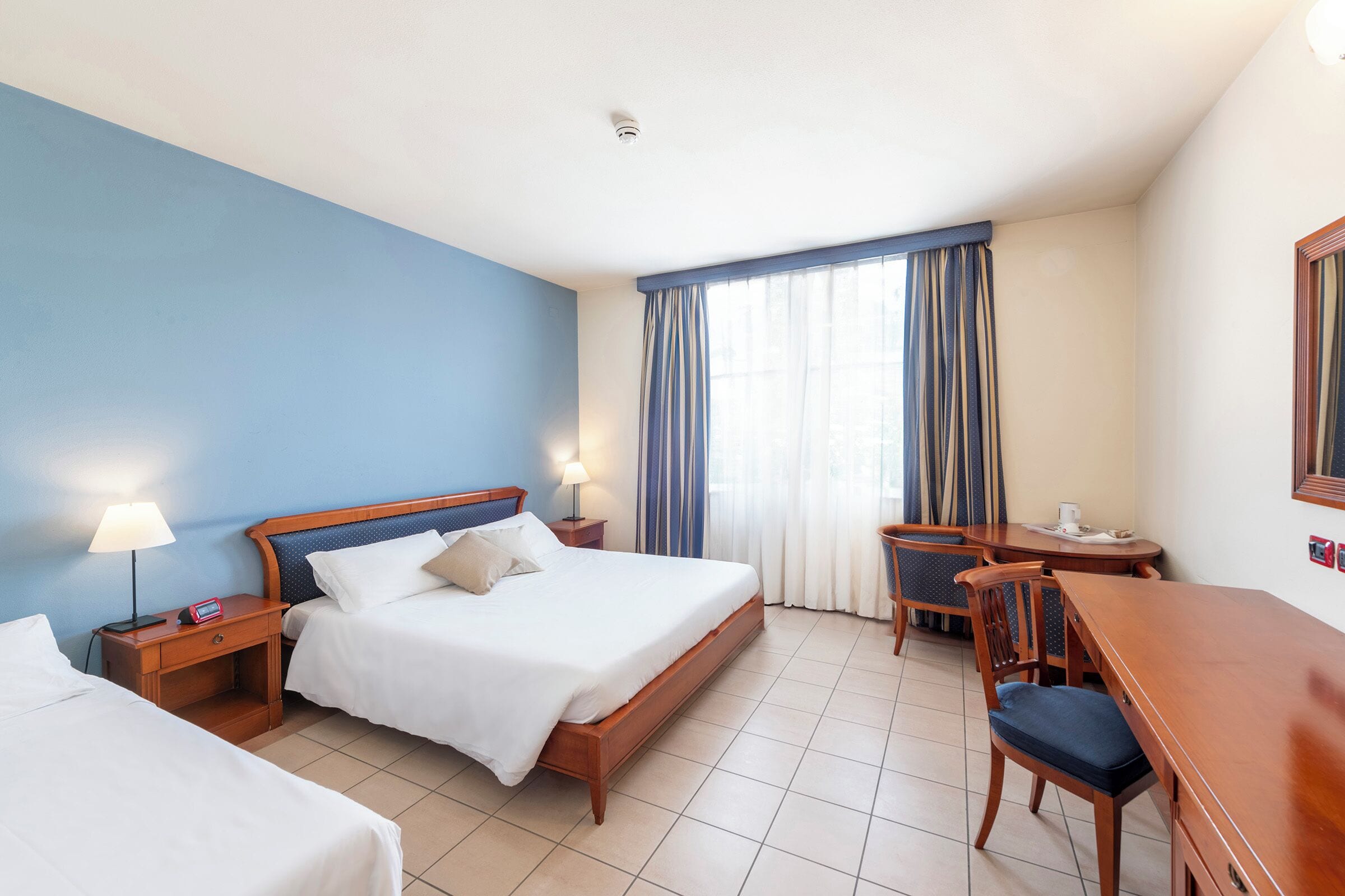 Een hotelkamer met een bed, nachtkastjes, een bureau en een stoel.