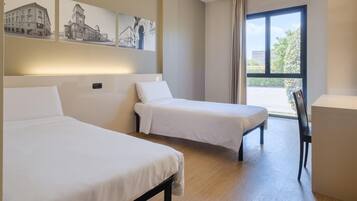 Una camera d'albergo con due letti, una scrivania e un'ampia finestra vista.