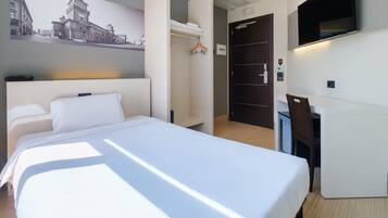 Ett hotellrum med en stor säng, ett skrivbord, en garderob och en tv.