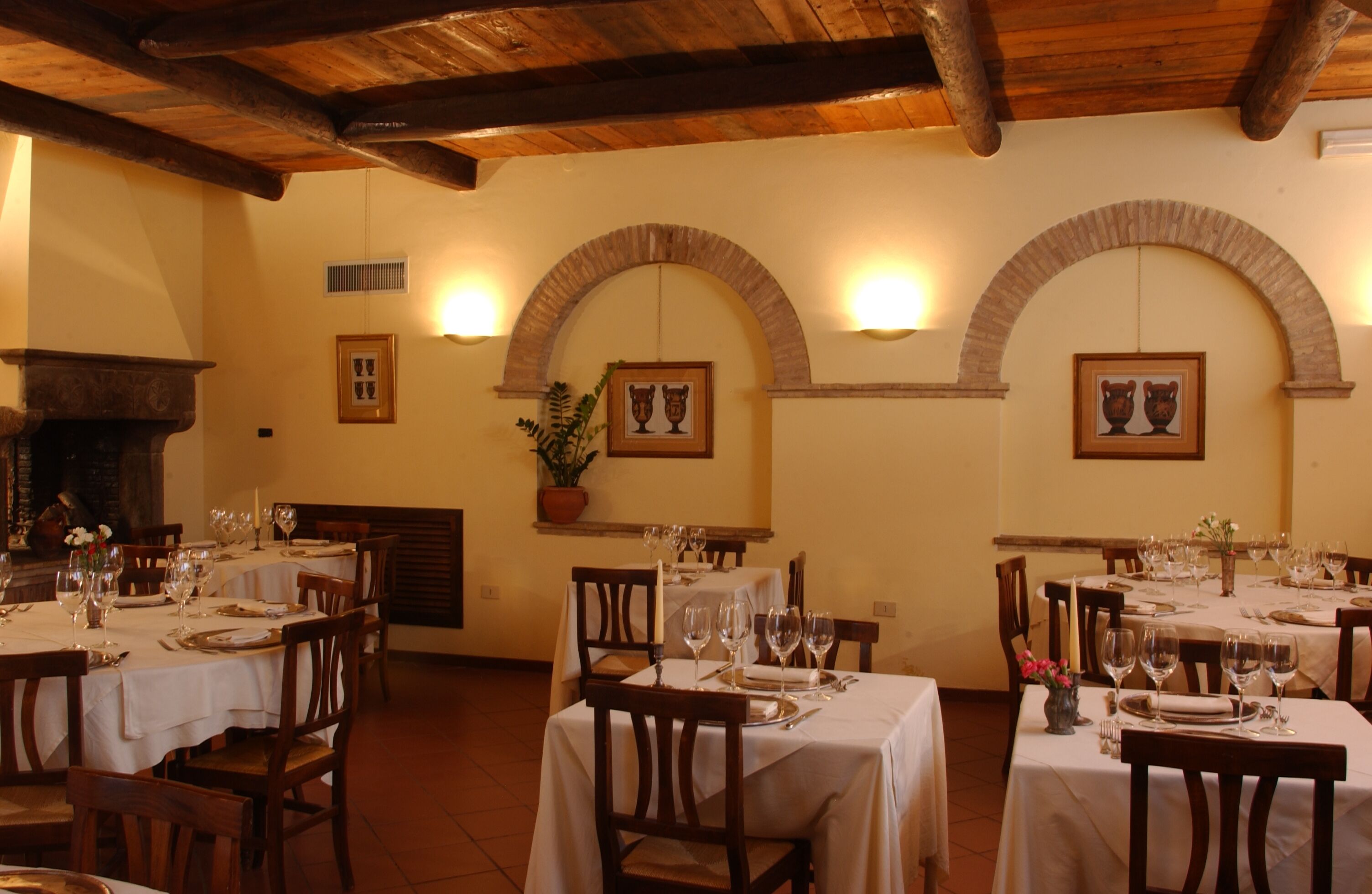 Un restaurante con varias mesas dispuestas para comer, sillas de madera y una chimenea de piedra.