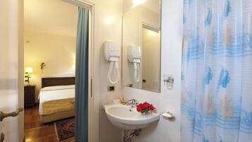 A hotel bathroom with a sink, mirror, and shower curtain.