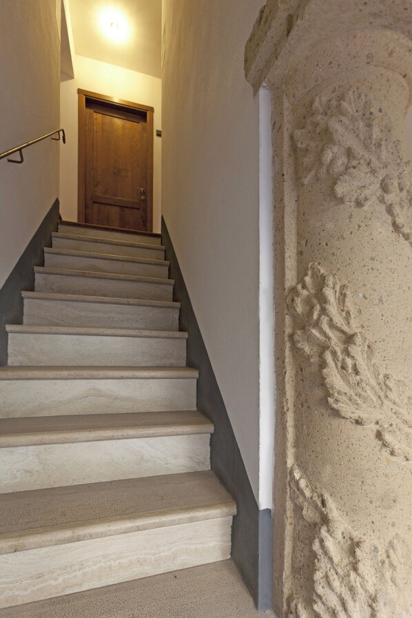 A staircase with a wooden door at the top, leading to a room with a white wall and a textured column. - Albergo Scilla (Sorano)