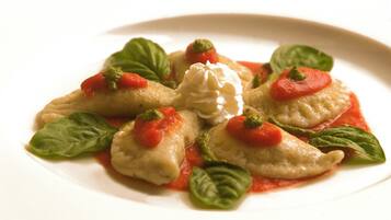 Pasta rellena con salsa de tomate y hojas de albahaca en un plato.