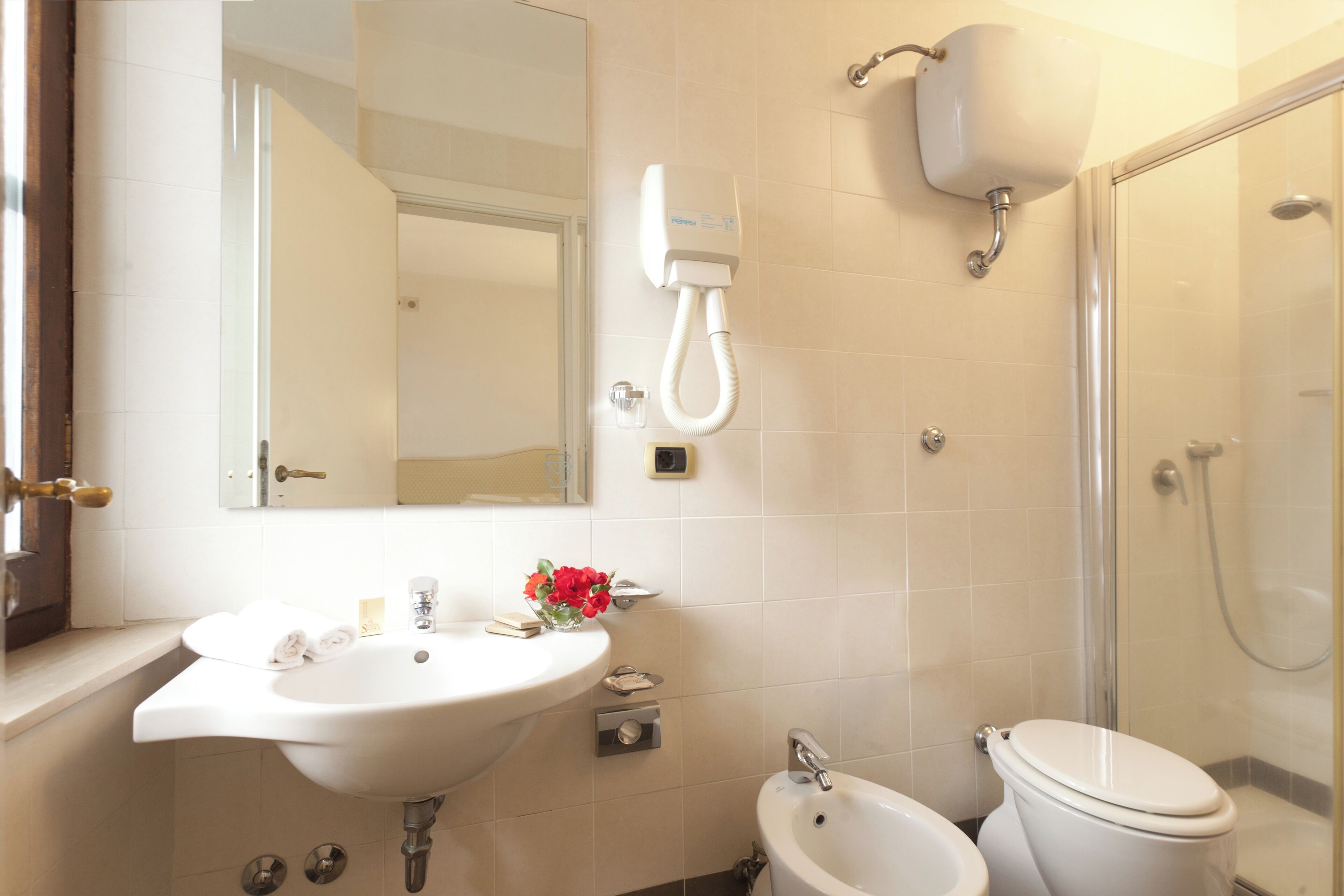 A bathroom with a sink, bidet, toilet, mirror, and a shower enclosure.