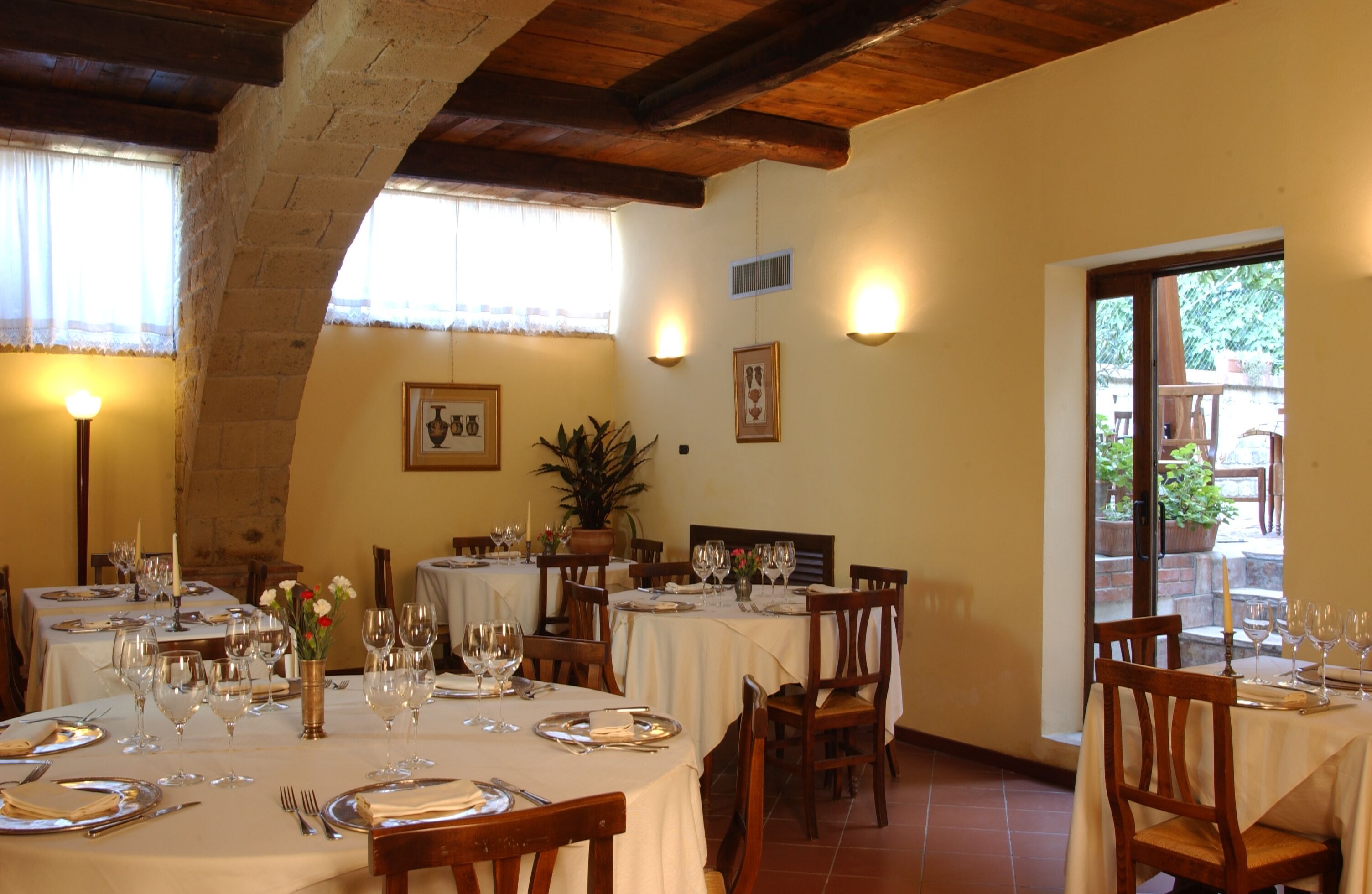Un restaurante con varias mesas dispuestas para comer, que presenta un interior rústico con vigas a la vista y paredes de piedra.