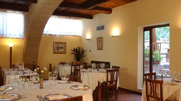 Un restaurante con varias mesas dispuestas para comer, que presenta un interior rústico con vigas a la vista y paredes de piedra.