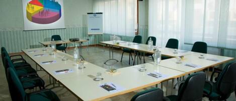 A conference room with a long table, chairs, a projector screen, and a whiteboard.