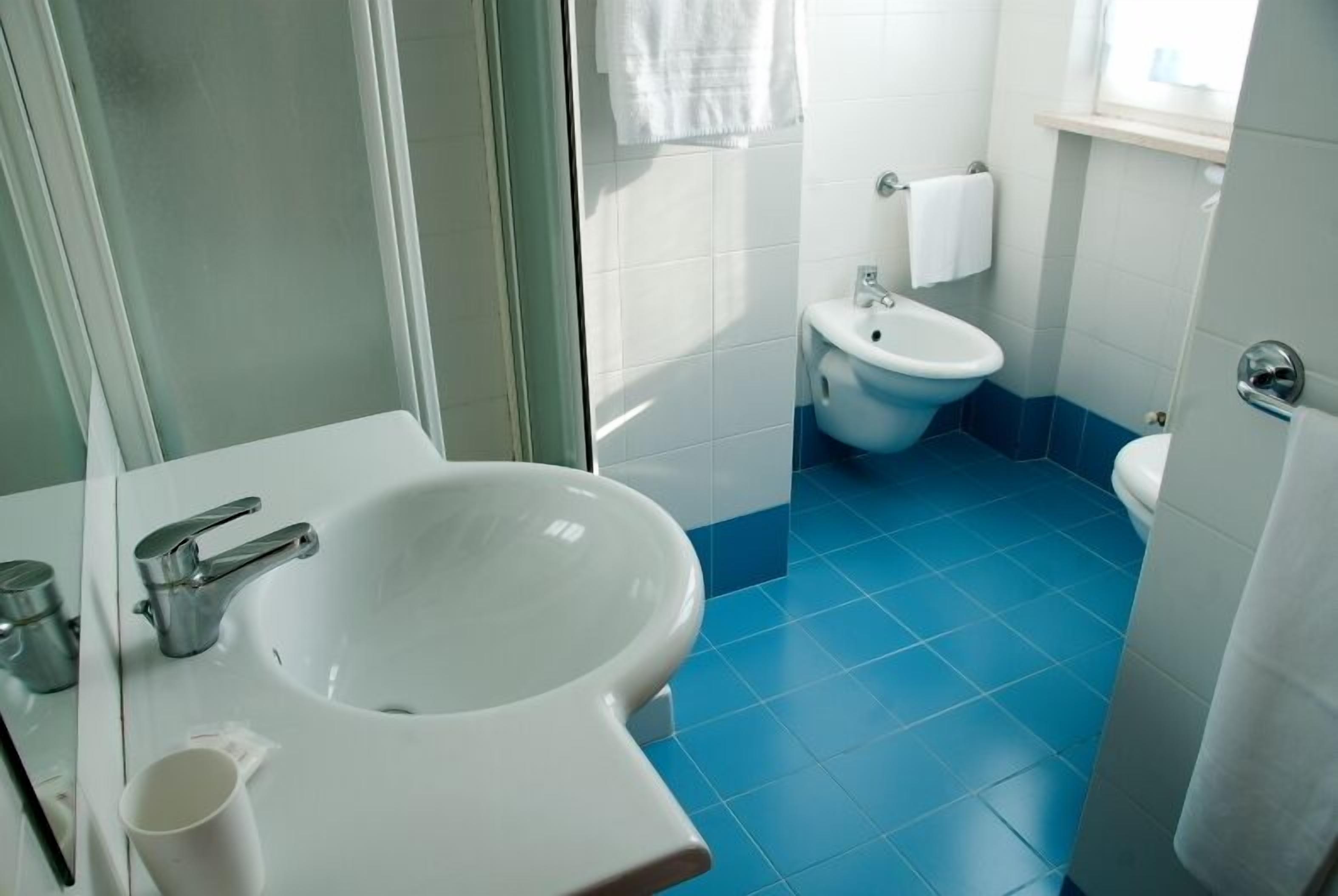 A bathroom with a white sink, a bidet, and a toilet.
