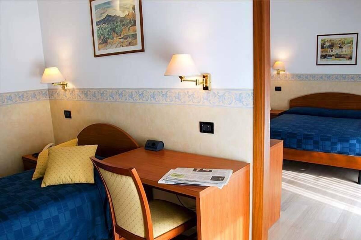 Ein Hotelzimmer mit zwei Betten, einem Holztisch und zwei Wandlampen.