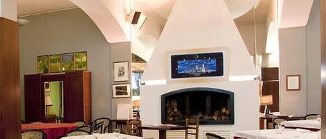 Un restaurante con mesas dispuestas para comer, una chimenea y cuadros en las paredes.