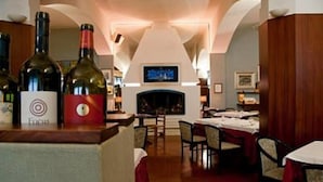 A restaurant with a fireplace, tables, and wine bottles on display. - Hotel Touring Falconara Marittima (Falconara Marittima)