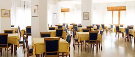 Un comedor amplio con varias mesas y sillas, dispuestas en filas.