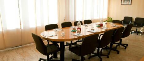 A conference room with a long table, black office chairs, and a wooden floor.