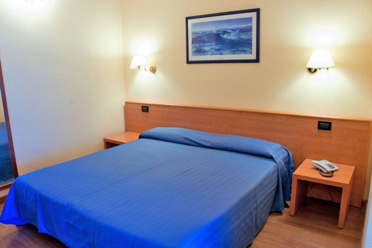 Ein Hotelzimmer mit einem Einzelbett, zwei Nachttischen und einem Beistelltisch mit einem Telefon.