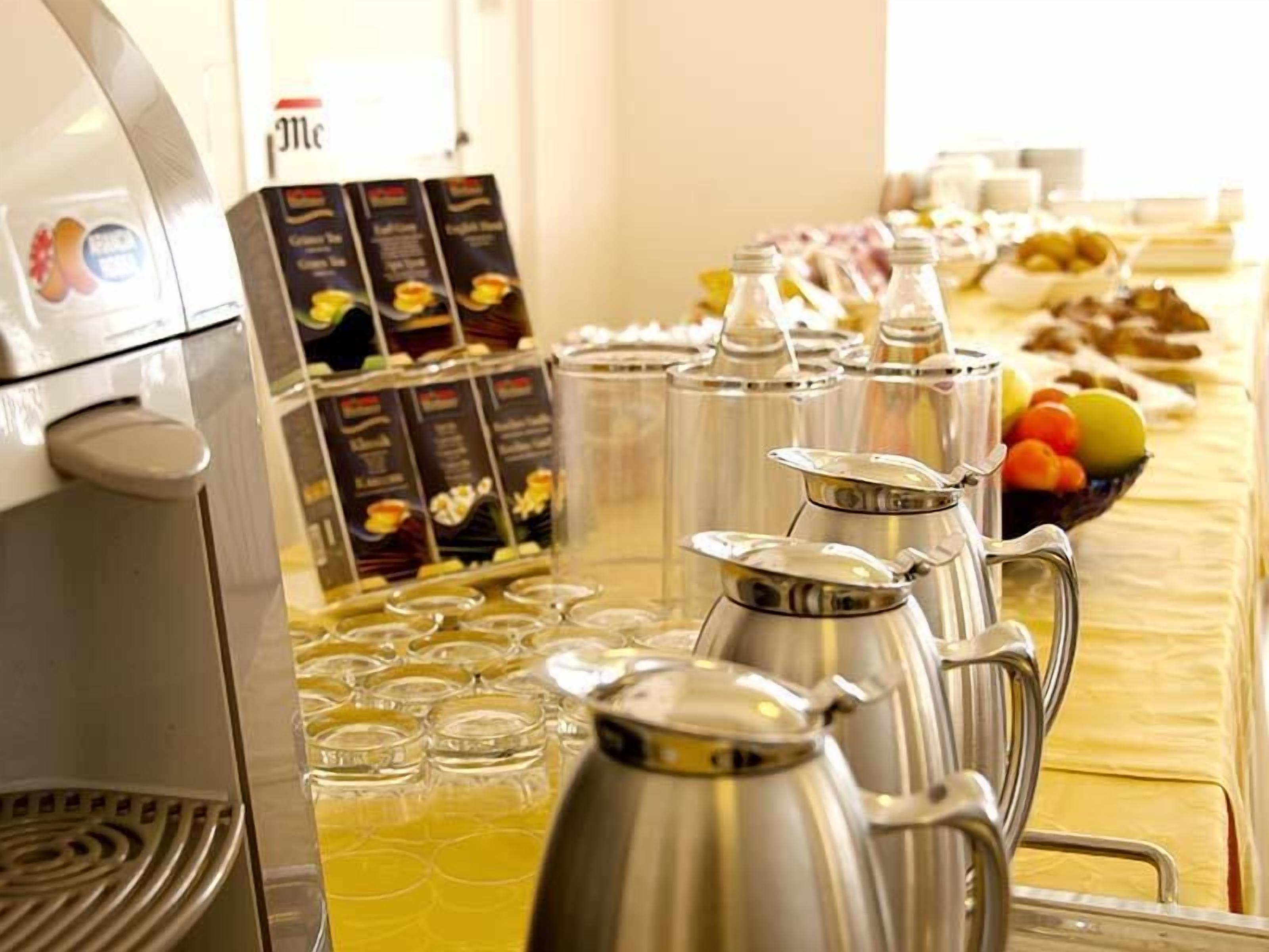 A buffet setup with coffee dispensers, a coffee machine, and a fruit bowl.