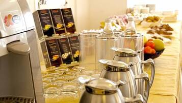 A buffet setup with coffee dispensers, a coffee machine, and a fruit bowl.