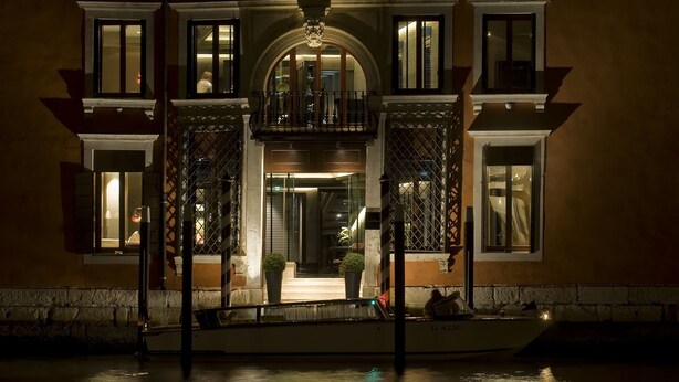 A historic building with a balcony, a boat docked in front, and a well-lit entrance. - Palazzo Barbarigo Sul Canal Grande (Venice)