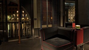 A modern interior with a sofa, a decorative wall, and a view of a canal. - Palazzo Barbarigo Sul Canal Grande (Venice)