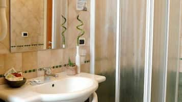 A bathroom with a sink, mirror, towel rack, and a glass shower enclosure.