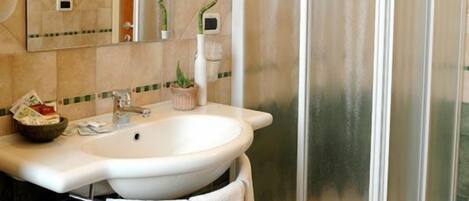 A bathroom with a sink, mirror, towel rack, and a glass shower enclosure.