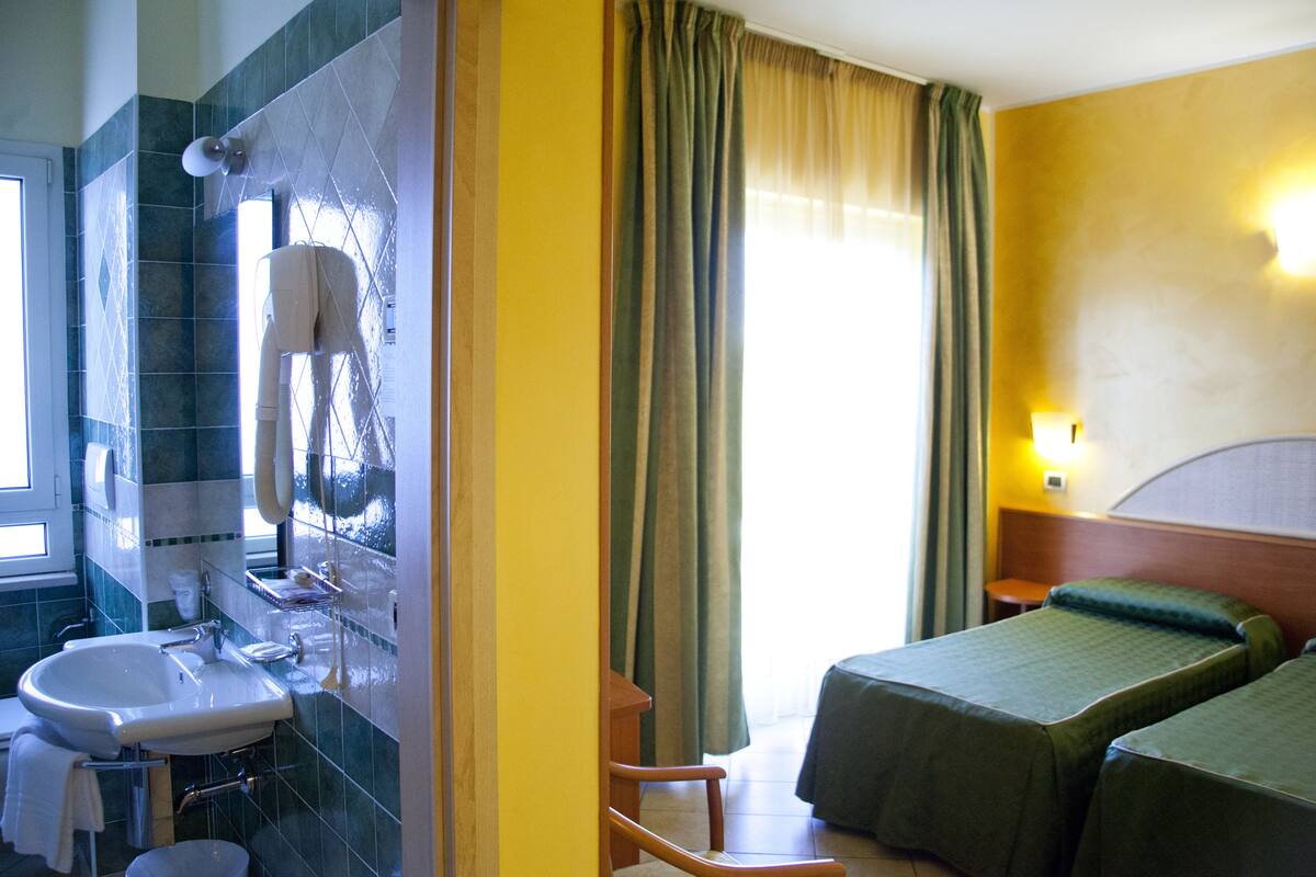 Une chambre d’hôtel avec une salle de bain, un lit, une chaise et une table de chevet.